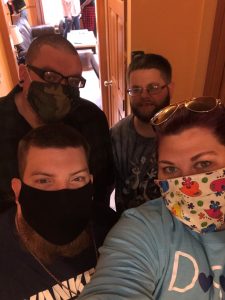 Women in blue shirt with facemask taking selfie with three males
