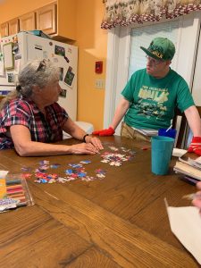 Woman and man with disabilities sitting at a table together doing a puzzle