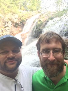 Matt left with a man in a bright green shirt in front of a waterfall