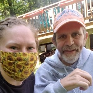 woman with yellow flower mask sitting with older man with beard