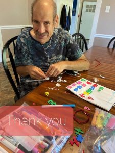 older man sitting at table with crafts text bubble at bottom that says thank you