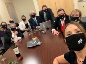 Group of people wearing black face masks all sitting around a table