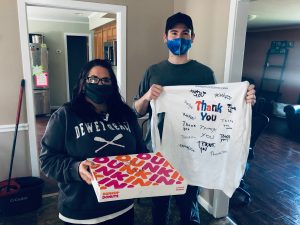two people wearing masks one holding a shirt and the other holding a dunkin donuts box