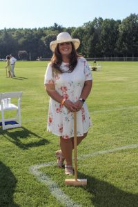 Women in white floral dress and sun hat posing on croquet field