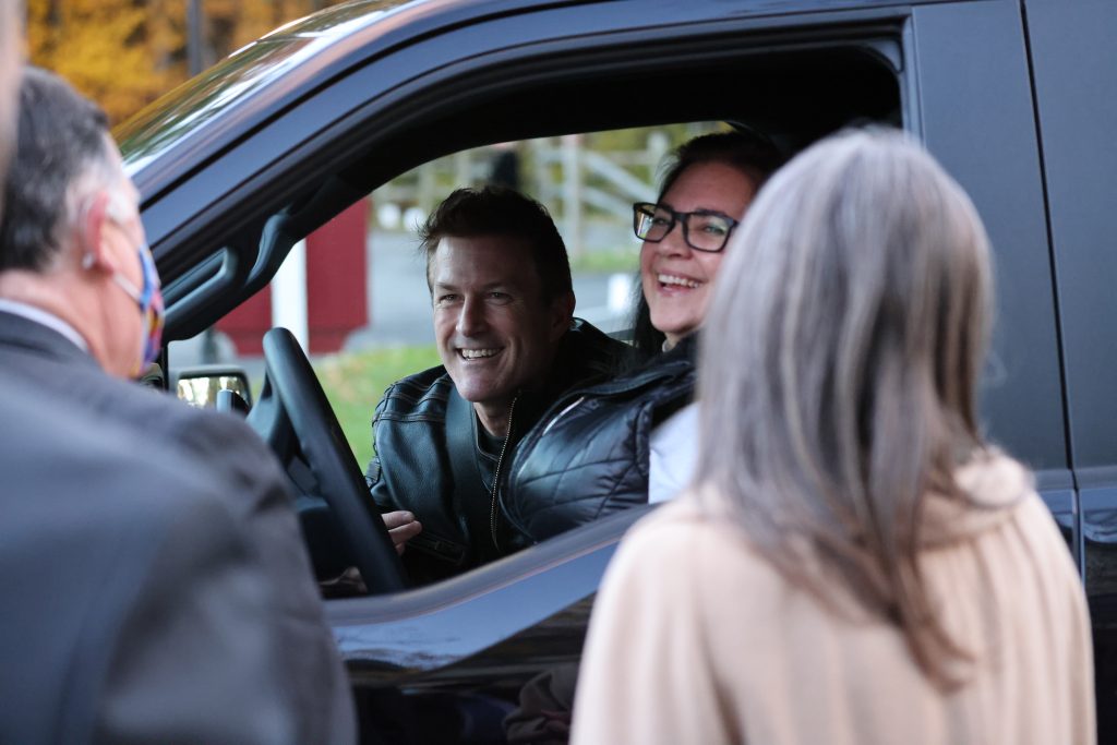 Two people smiling in their car with two people looking into their cars at AIM Services Vin Le Soir 2021