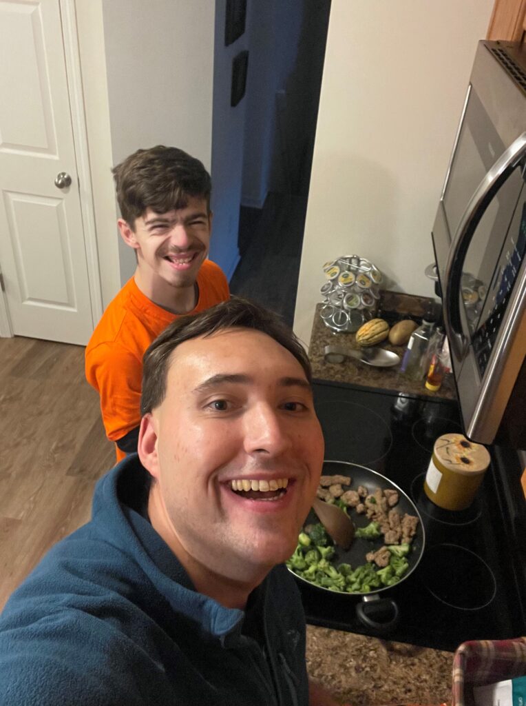 Andrew with a friend standing over a stove cooking together