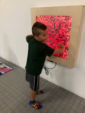 young boy touching light up screen on a wall