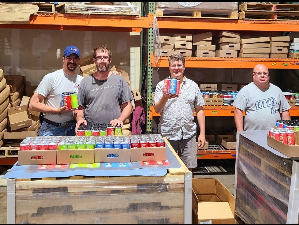 group of people holding beer over palettes of beer