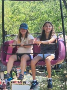 two girls riding a chair lift at an amusement park